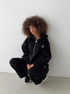 Women's black zip-up hoodie with hood, pink logo and front pouch pocket