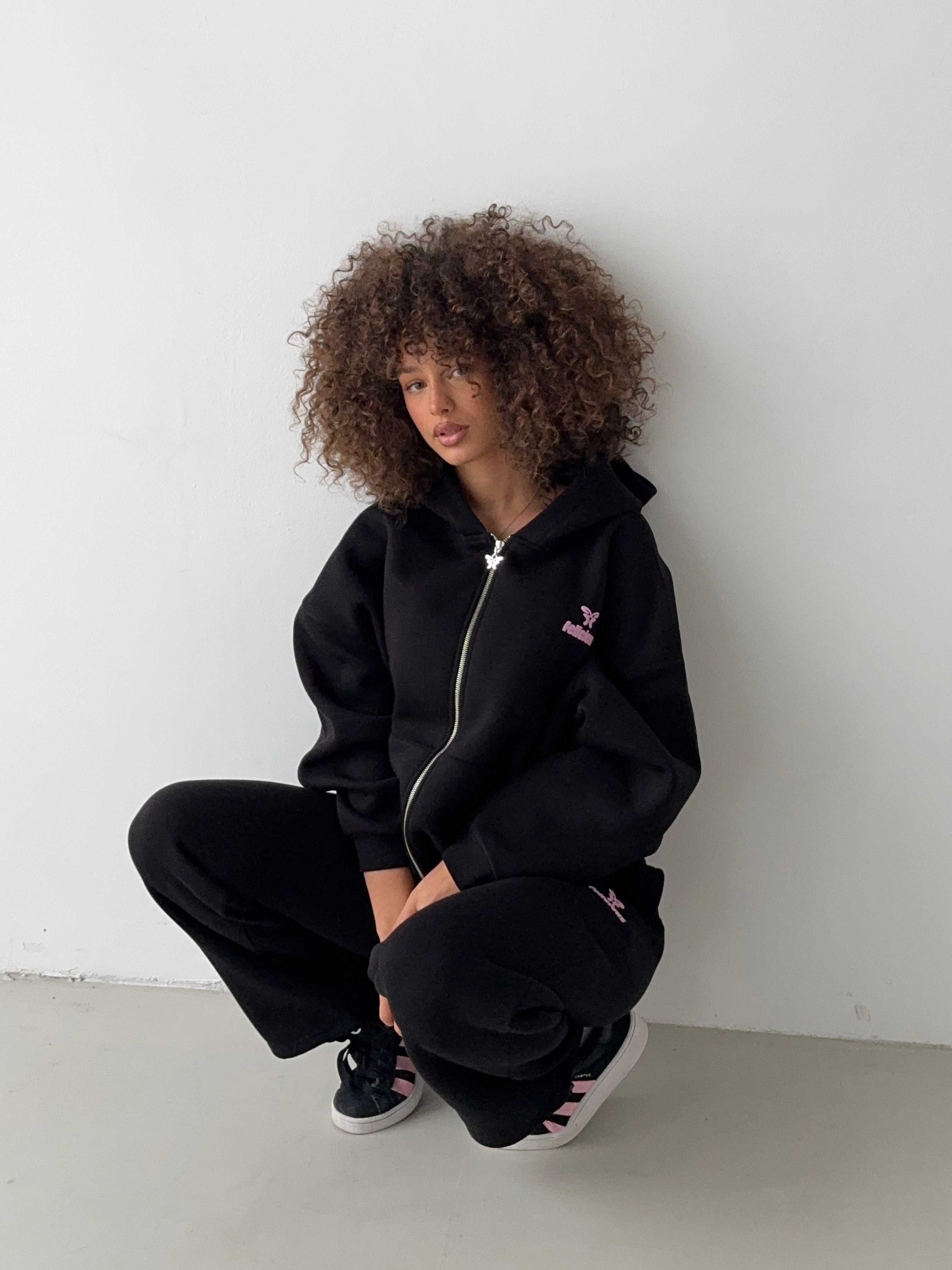 Women's black zip-up hoodie with hood, pink logo and front pouch pocket