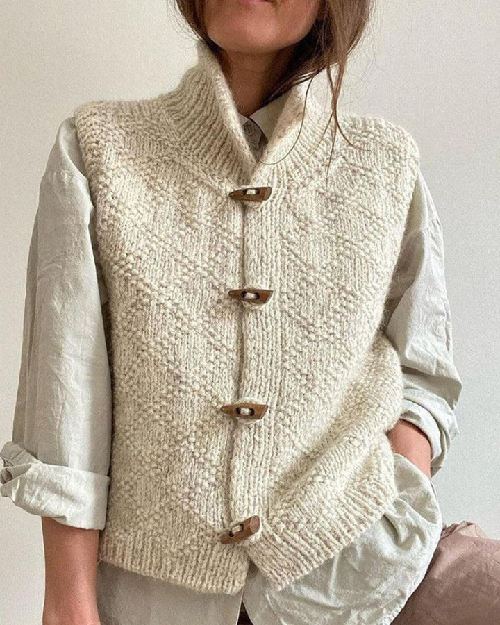 Cream sleeveless knitted cardigan with funnel neck and toggle fastenings
