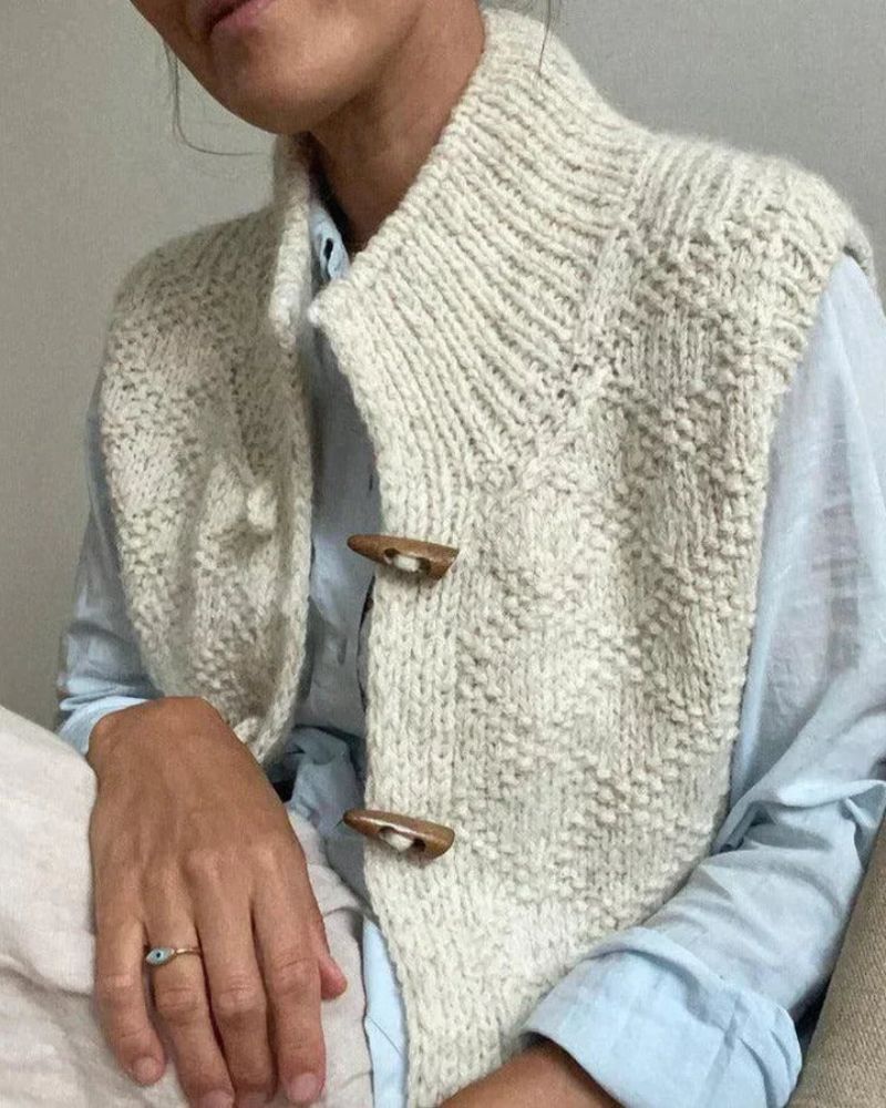 Cream sleeveless knitted cardigan with funnel neck and toggle fastenings