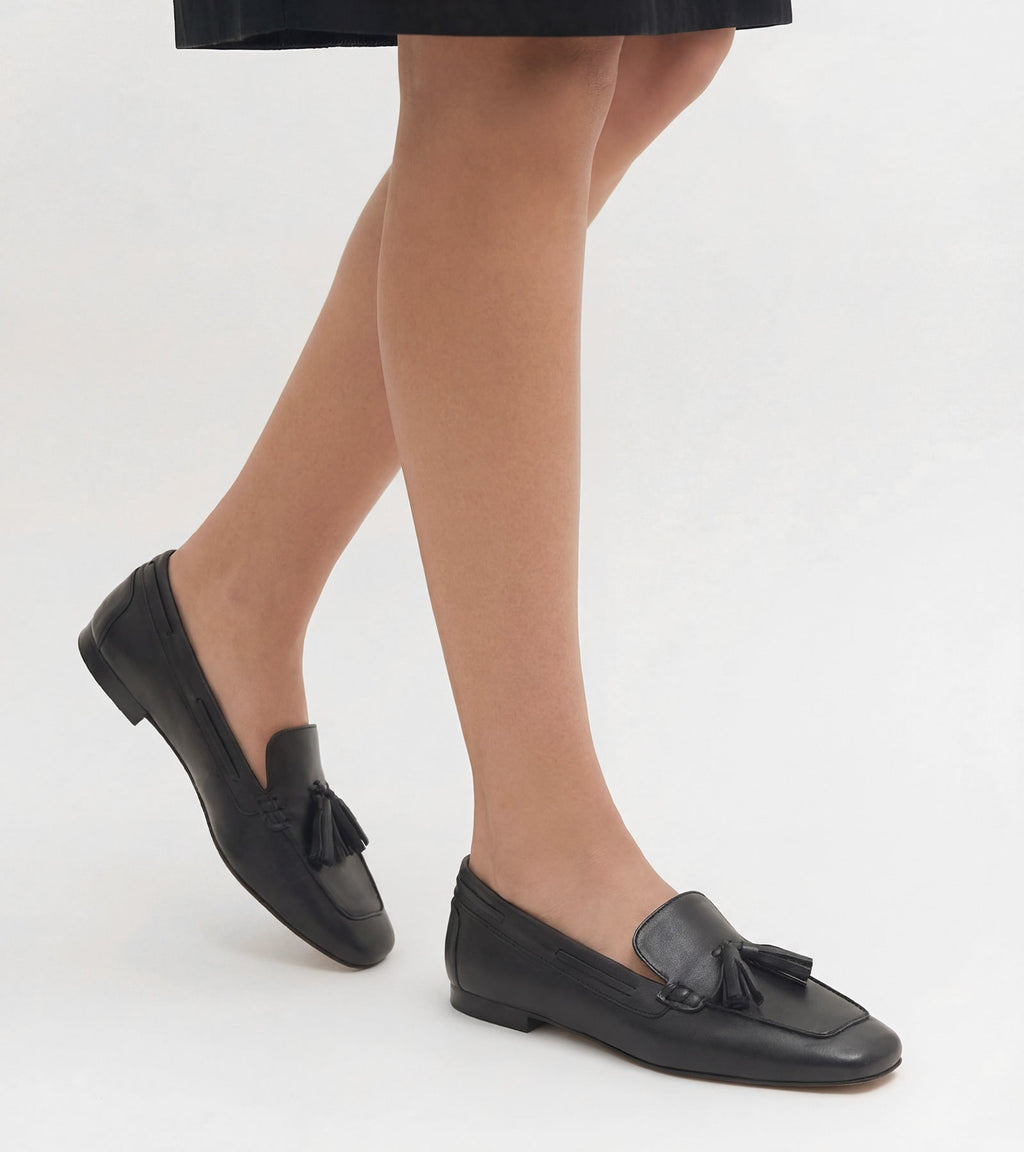 Women's black slip-on loafers with tassel detailing and flat heels