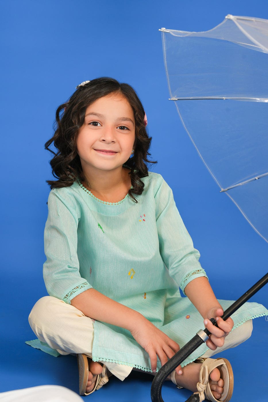 Girl wearing a green long-sleeve tunic shirt with small colourful embroidered motifs