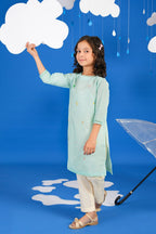 Girl wearing a green long-sleeve tunic shirt with small colourful embroidered motifs