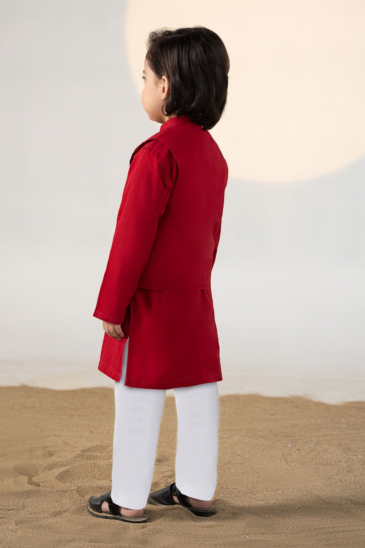 Child wearing a red traditional kurta suit set with matching trousers