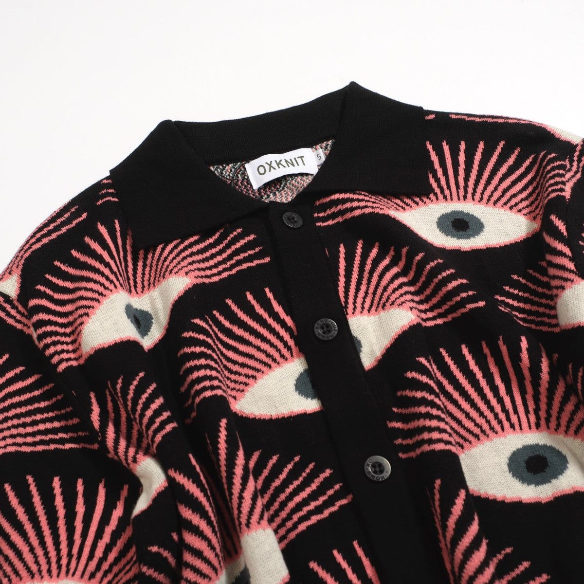 Men's black knitted polo shirt with repeated pink, cream and grey eye pattern