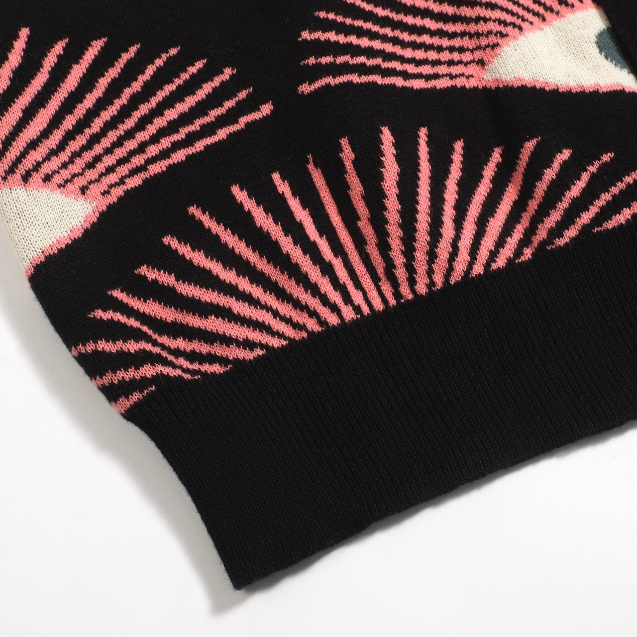 Men's black knitted polo shirt with repeated pink, cream and grey eye pattern