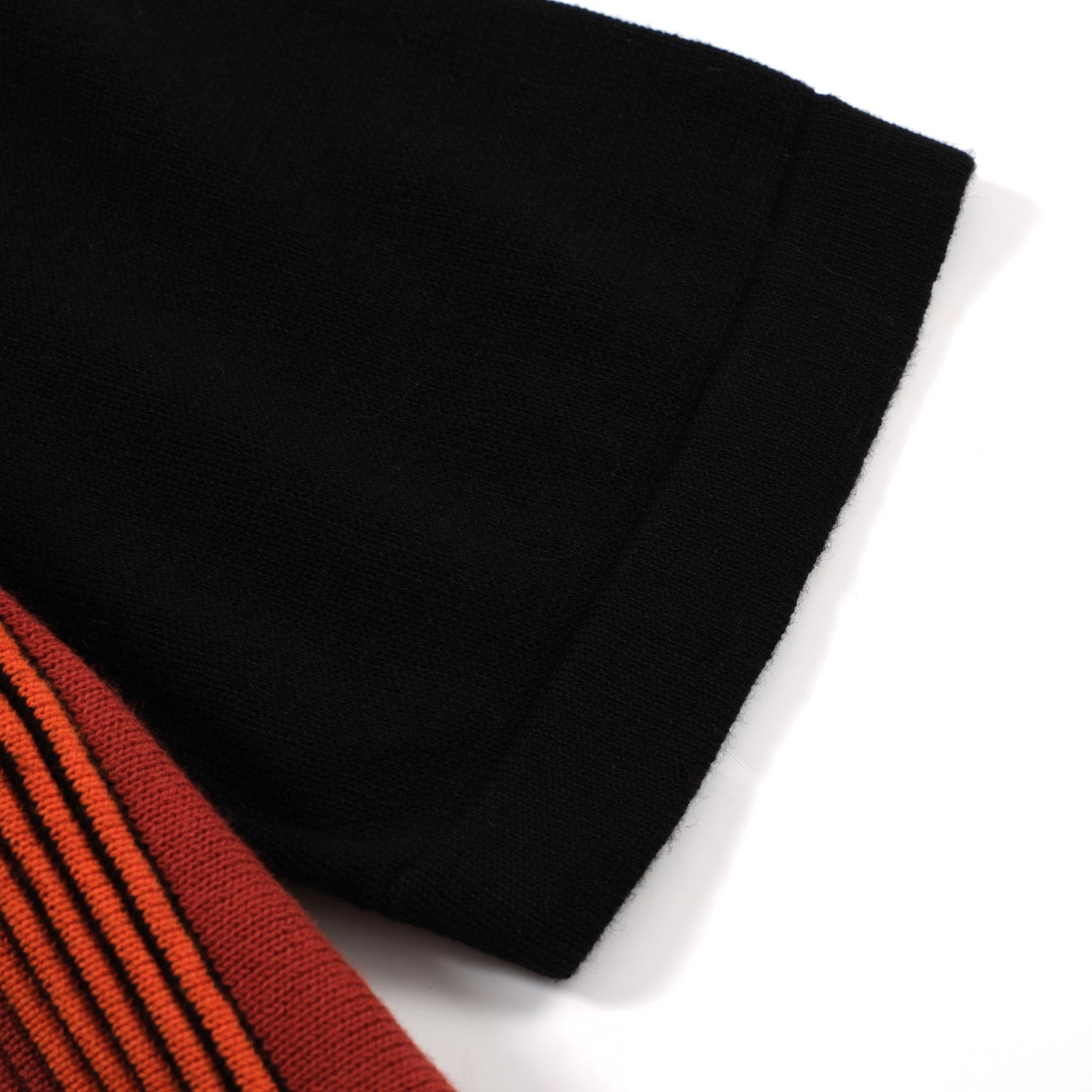 Men's black knit polo with red, orange and white vertical stripes