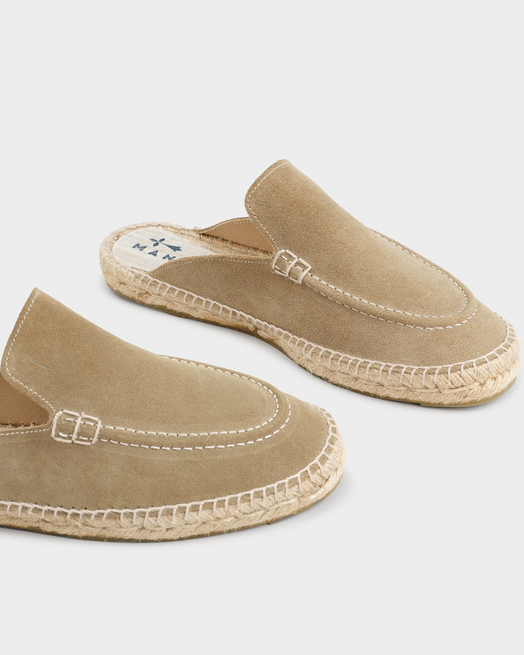 Beige unisex loafer mules with rounded toes, open heels and flat woven-effect soles