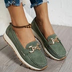 Women's green slip-on loafers with gold-tone buckle and white soles