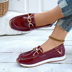 Women's burgundy glossy loafers with gold chain detail and flat textured soles