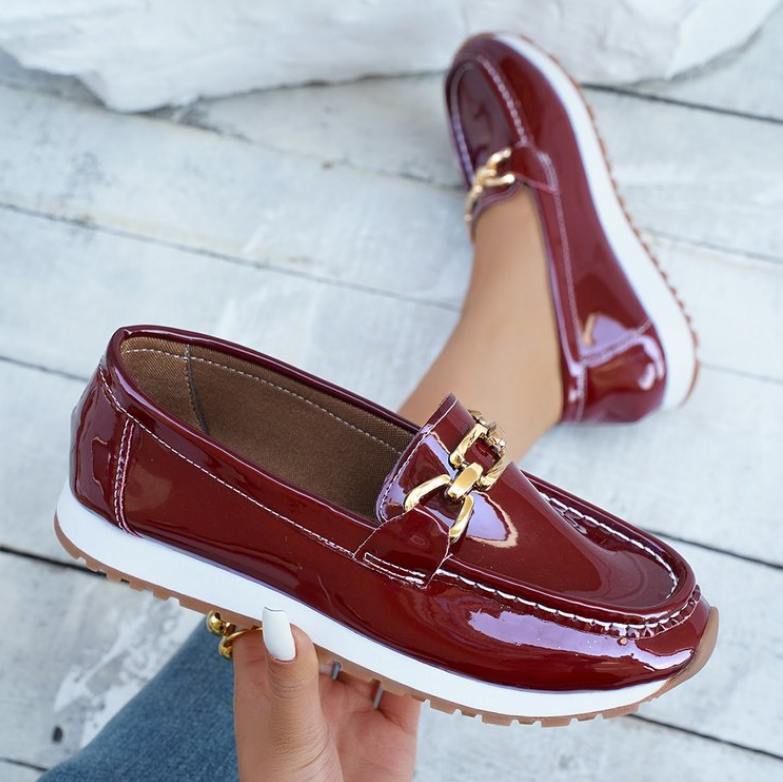 Women's burgundy glossy loafers with gold chain detail and flat textured soles