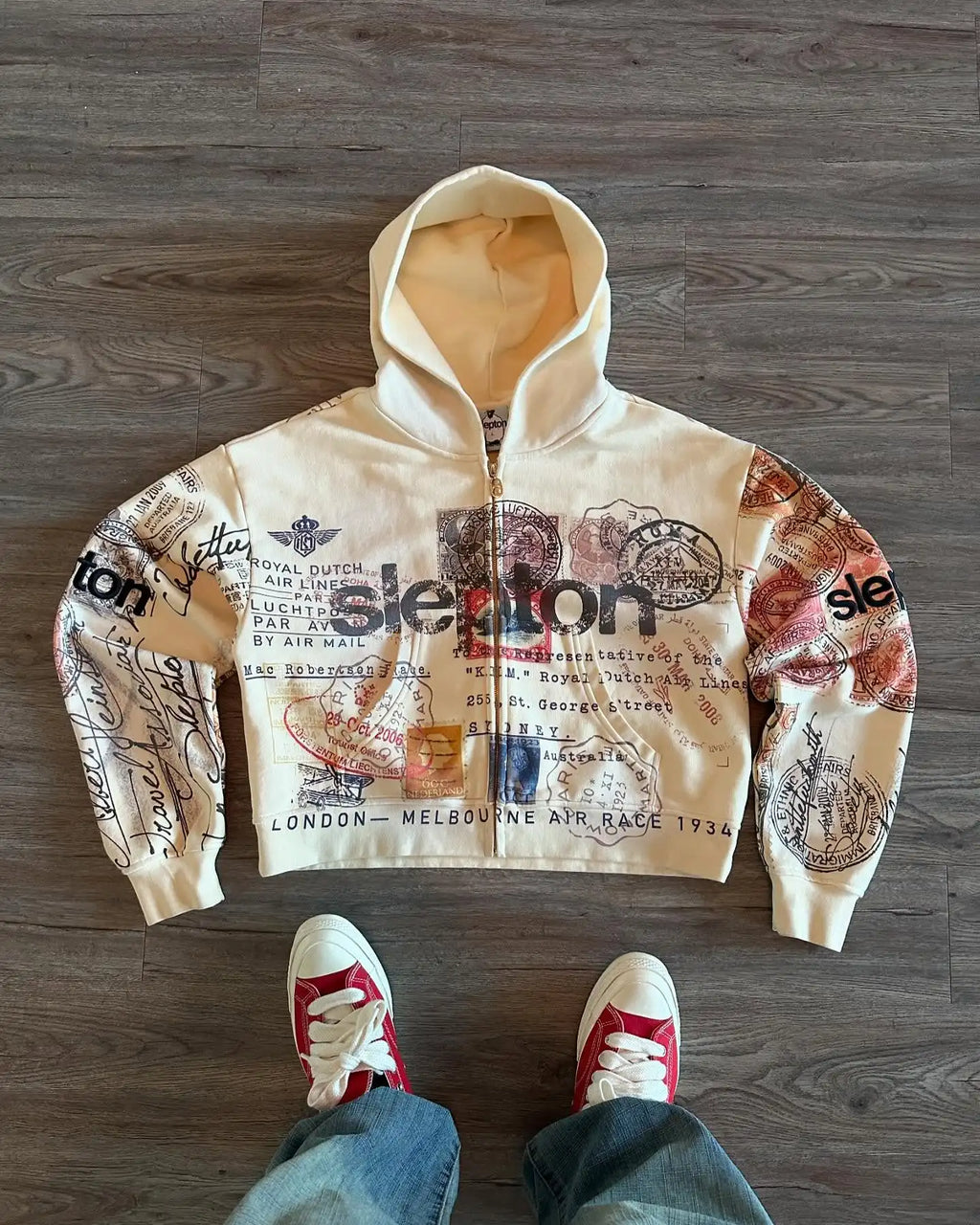 Beige hooded zip hoodie with postal stamp graphics and long sleeves