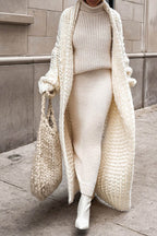 Women's longline chunky knit cardigan worn open over a high-neck jumper