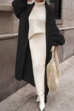 Women's longline chunky knit cardigan worn open over a high-neck jumper