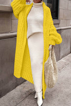 Women's longline chunky knit cardigan worn open over a high-neck jumper