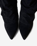 Women's black slouchy knee-high boots with pointed toes and buckled straps