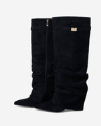 Women's black slouchy knee-high boots with pointed toes and buckled straps