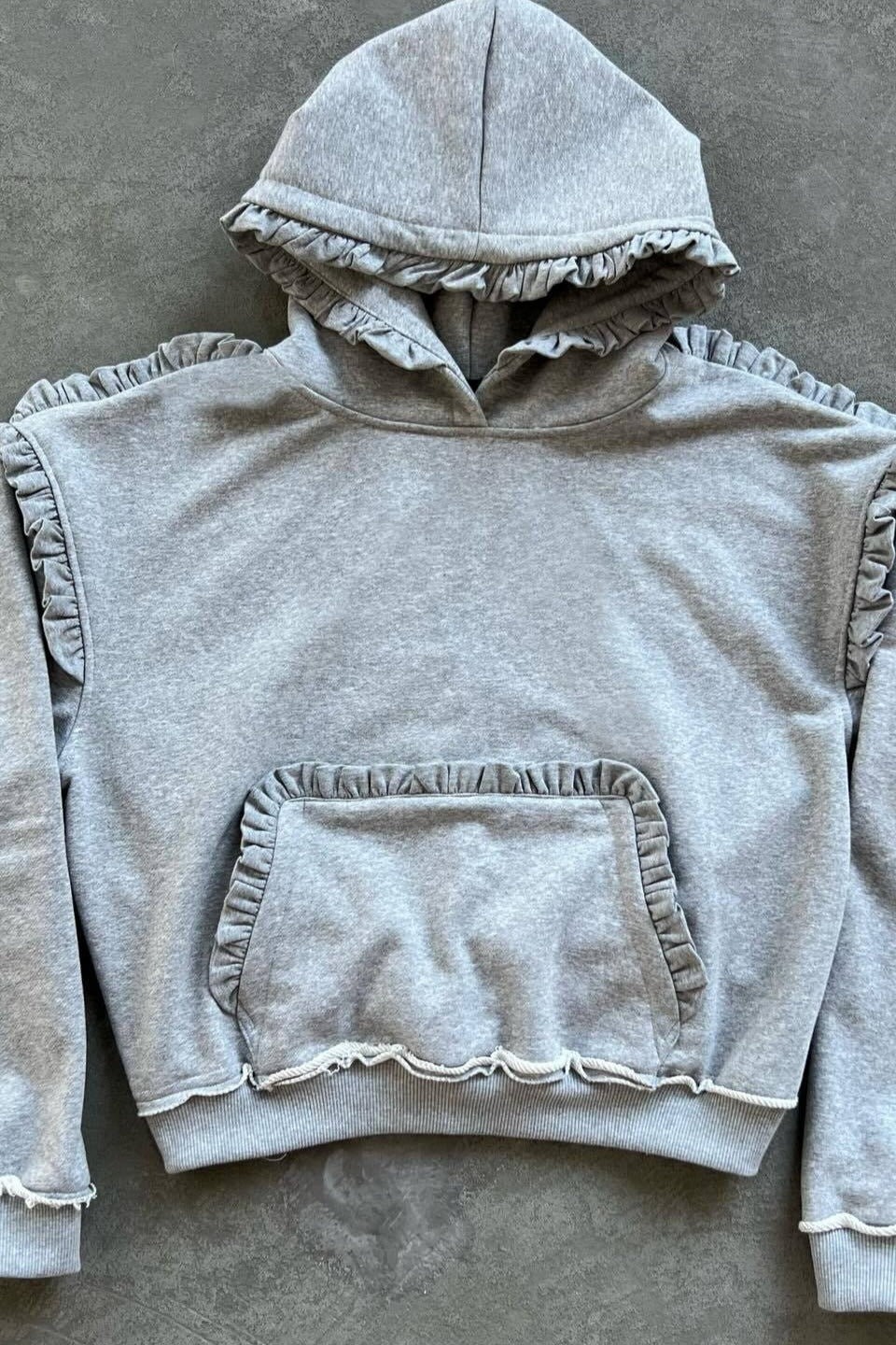 Women's grey pullover hoodie with ruffle trim around the hood and sleeves
