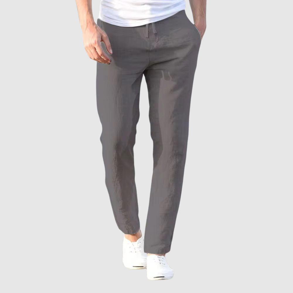 Men's beige relaxed-fit trousers with drawstring waist and flat front, full-length view.