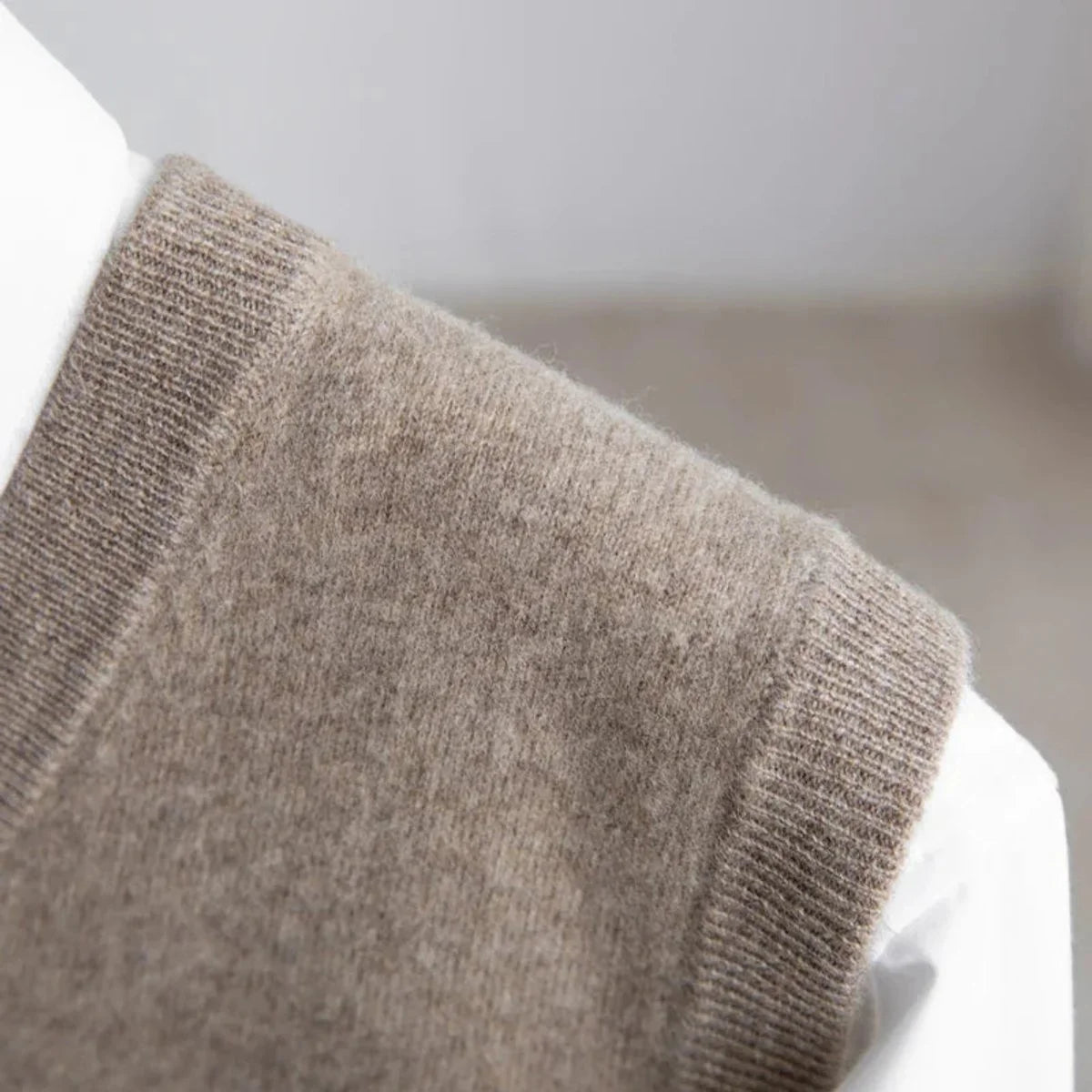 Men's V-neck knitted sweater vest layered over a white shirt