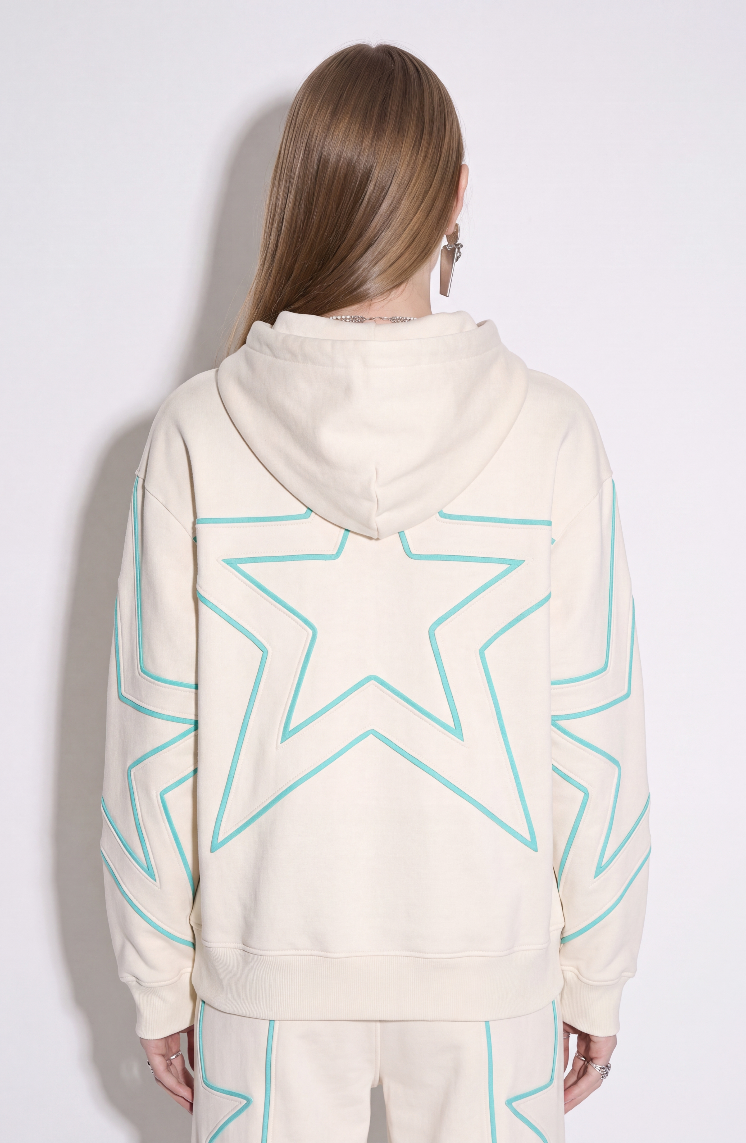 Cream hoodie with turquoise outlined star pattern, drawstring hood and front pouch pocket