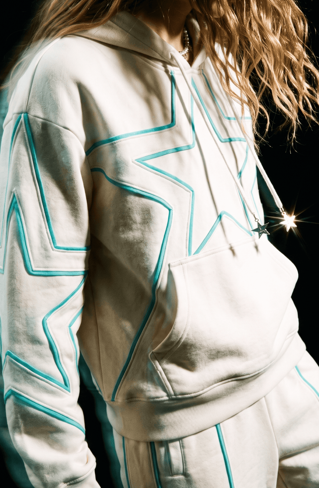 Cream hoodie with turquoise outlined star pattern, drawstring hood and front pouch pocket