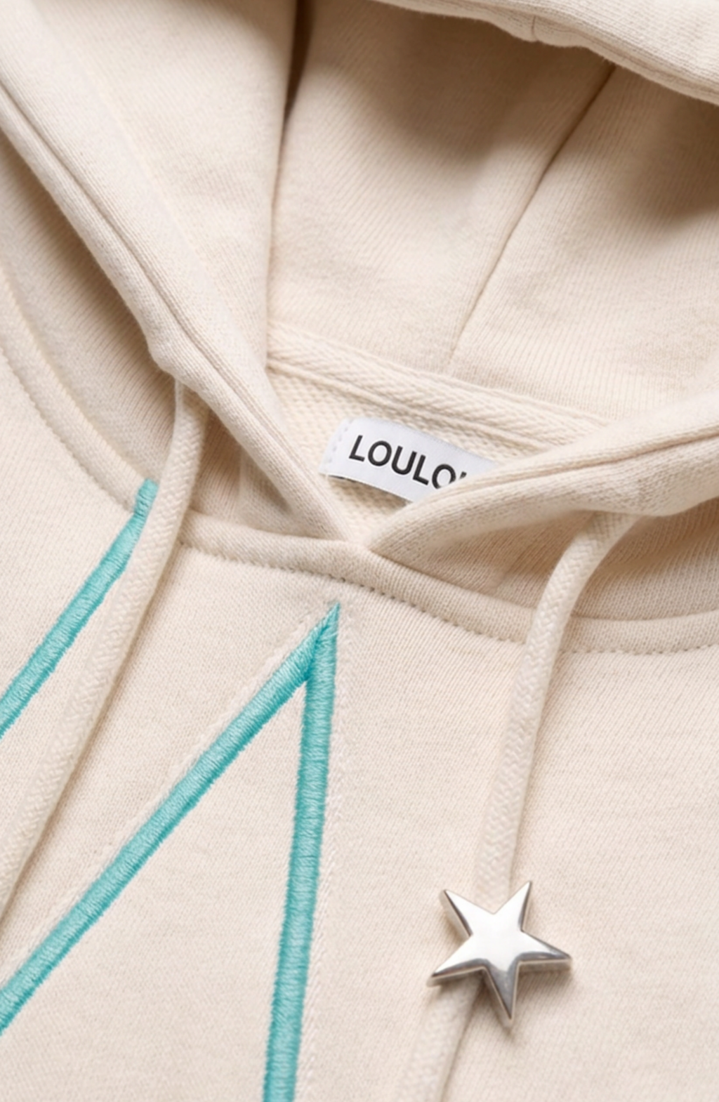 Cream hoodie with turquoise outlined star pattern, drawstring hood and front pouch pocket