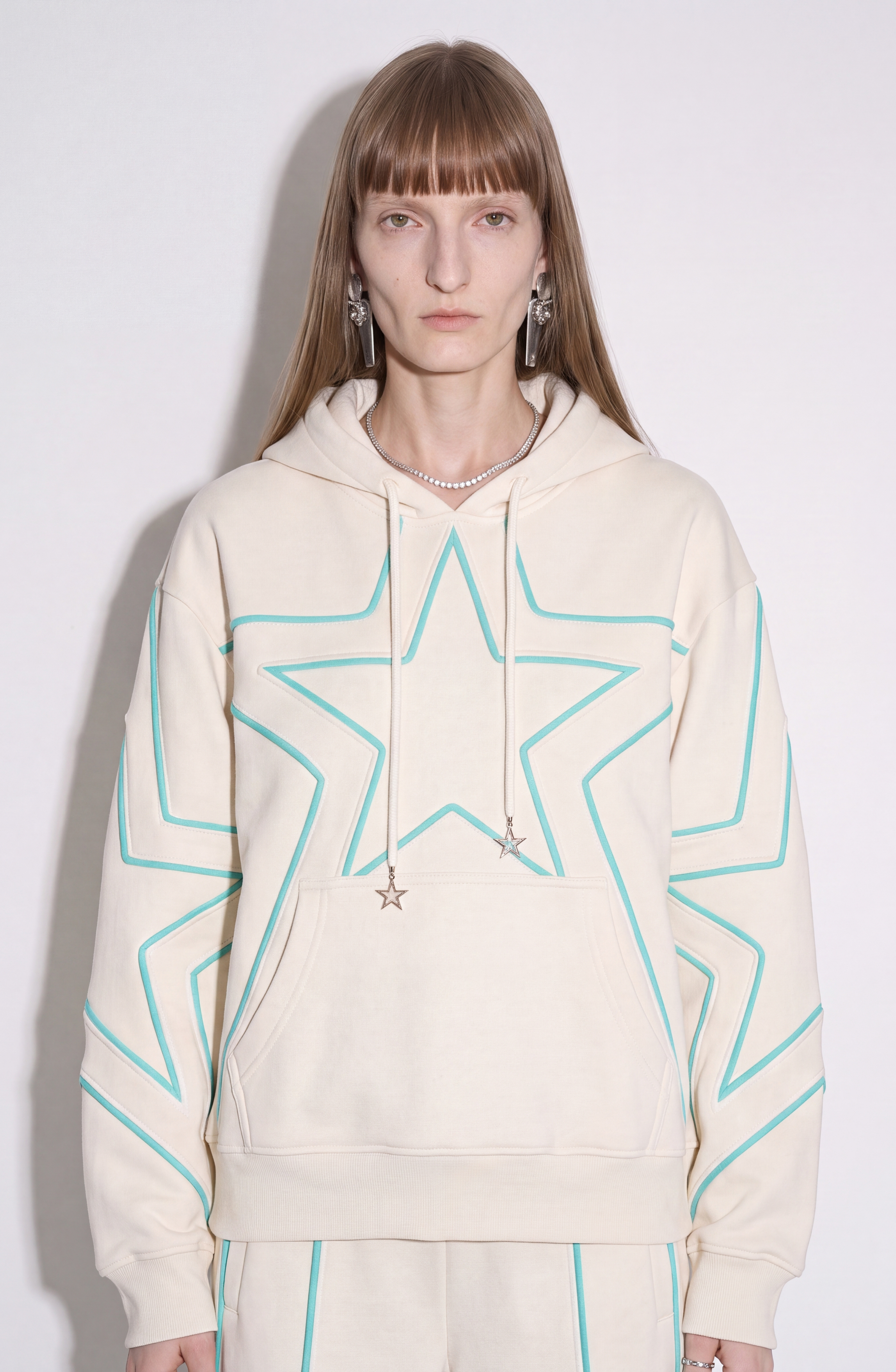 Cream hoodie with turquoise outlined star pattern, drawstring hood and front pouch pocket