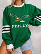 Women's green sweatshirt with eagle football graphic and striped sleeves