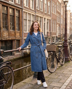 Women's long denim trench coat with lapels, buttons, belt and cuff straps