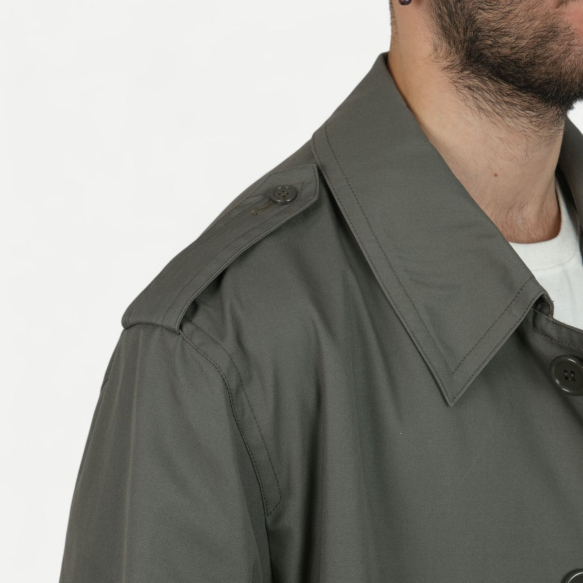 Men's muted green long raincoat with button front, pointed collar and shoulder tabs