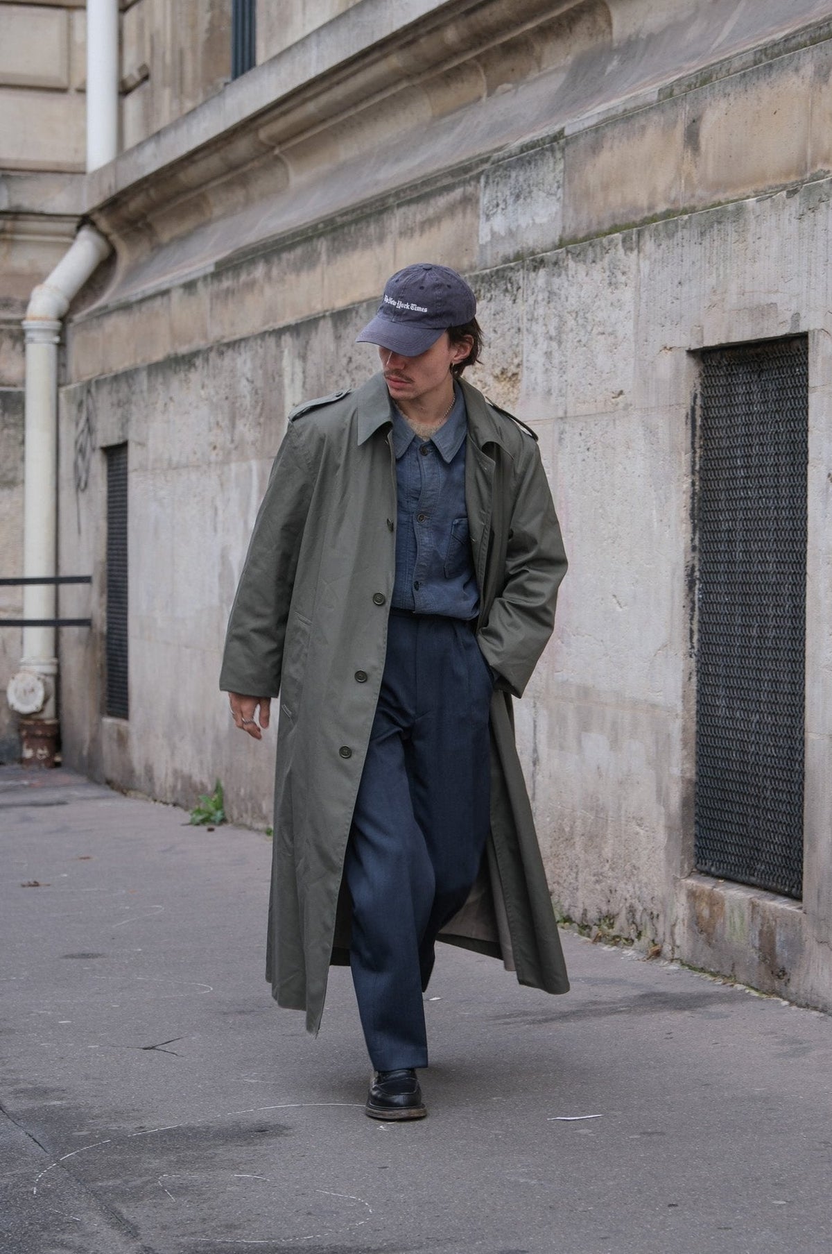 Men's muted green long raincoat with button front, pointed collar and shoulder tabs